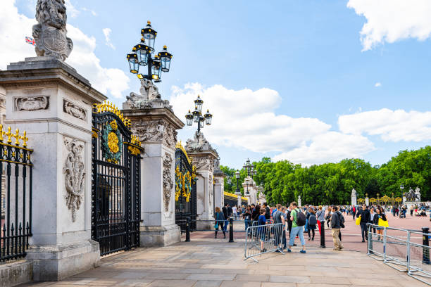英国の道路を歩く多くの人々の観光客とバッキンガム宮殿の金のゲートフェンス - 13581 ストックフォトと画像