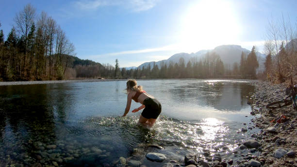 istock Female mountain biker jumps into mountain river 1220847686