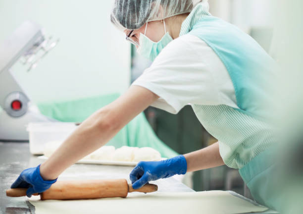 Female working in a kitchen wearing protective gloves and mask
