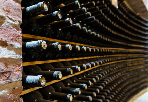 ワイナリーのワインセラーに保管されている赤ワインボトル - ワイン貯蔵庫 写真 ストックフォトと画像