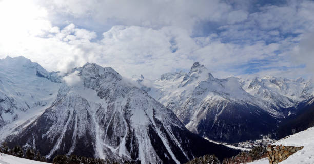 istock Panoramic view of snowy mountains peaks in the clouds blue sky Caucasus 1220854522