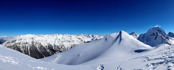 istock Panoramic view of snowy mountains peaks in the clouds blue sky Caucasus 1220854524