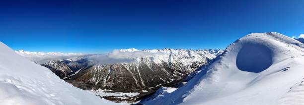 istock Panoramic view of snowy mountains peaks in the clouds blue sky Caucasus 1220854526