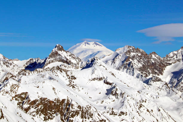 Snowy Mountains peaks in the clouds blue sky
