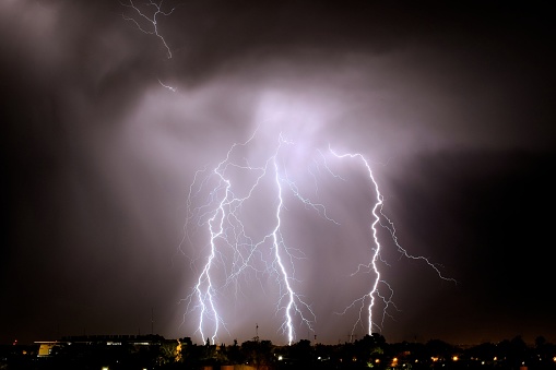 Lightning on background of night sky. Weather and climate. Flash of lightning. Natural disaster. Dark dramatic sky. Storm