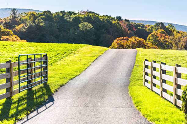 Photo of View of road driveway through scenic farm fields land and appalachian mountains in Bath County, Virginia with fence and open gate