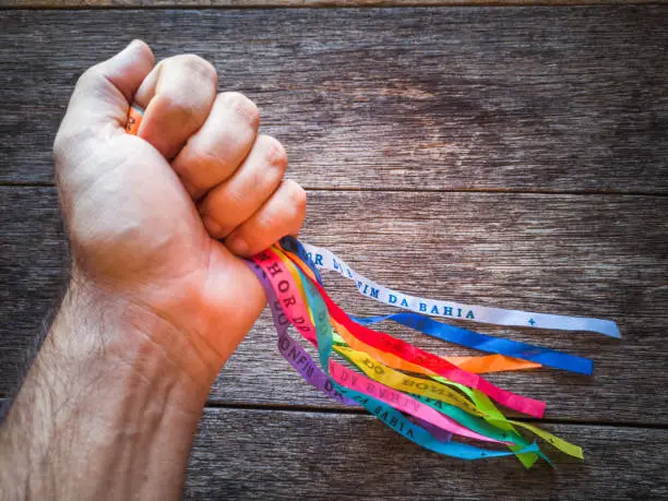 Photo of Hands holding Colorful ribbons of Senhor do Bonfim. Symbol of faith of the Senhor do Bonfim church.