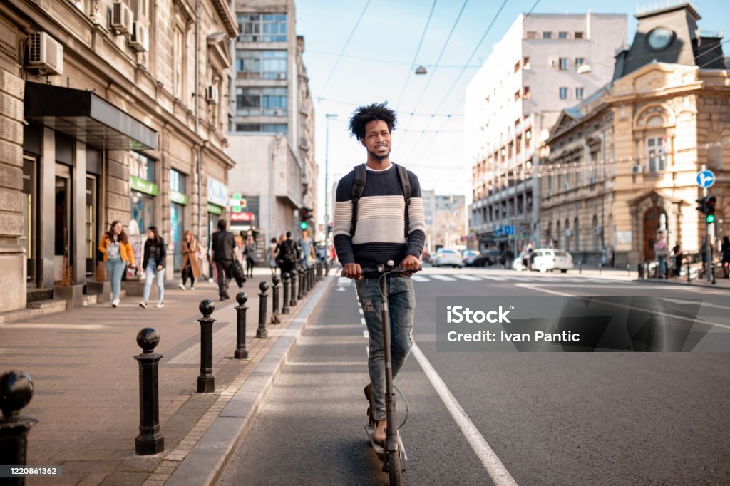 Young Man With Curly Hairstyle Riding An Electric Push Scooter Around The  City Stock Photo - Download Image Now - iStock