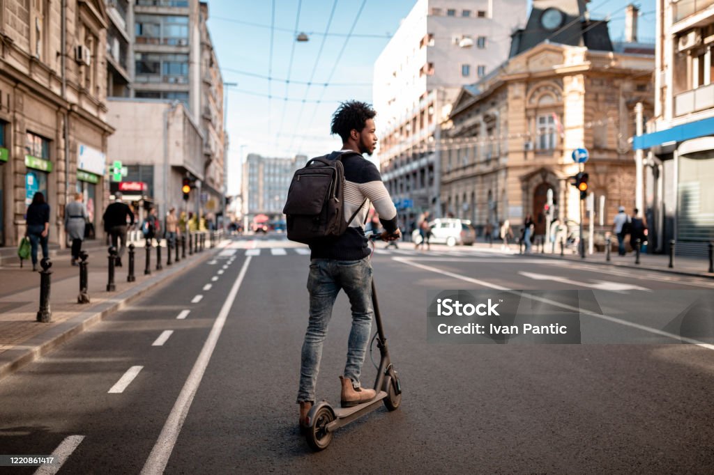 Young Man With Curly Hairstyle Riding An Electric Push Scooter Around The  City Stock Photo - Download Image Now - iStock