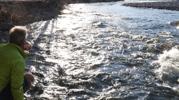 istock Man relaxes by riverbank in the morning 1220867483