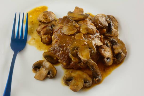 Salisbury steak with mushroom sauce Salisbury steak with mushroom sauce with blue fork on white plate salisbury steak stock pictures, royalty-free photos & images