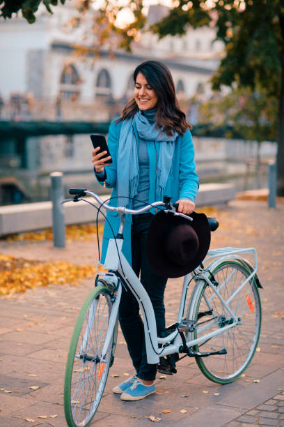 istock Woman Enjoying Autumn and Texting on her Mobile Phone While Pushing Her Bicycle 1220868618
