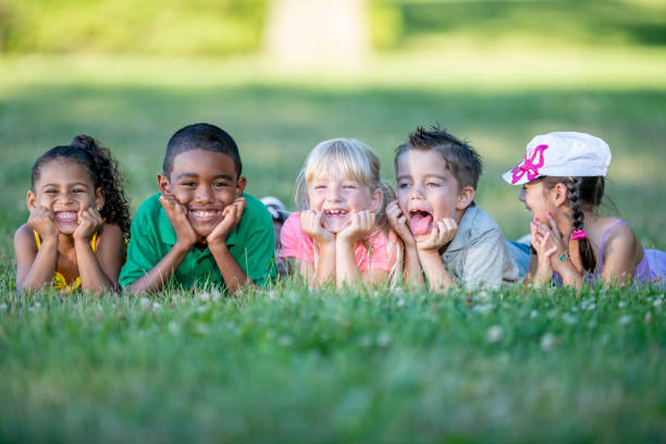 istock Group of kids lying in the grass together 1220873085