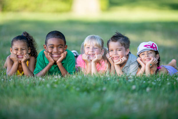 istock Group of kids lying in the grass together 1220873090