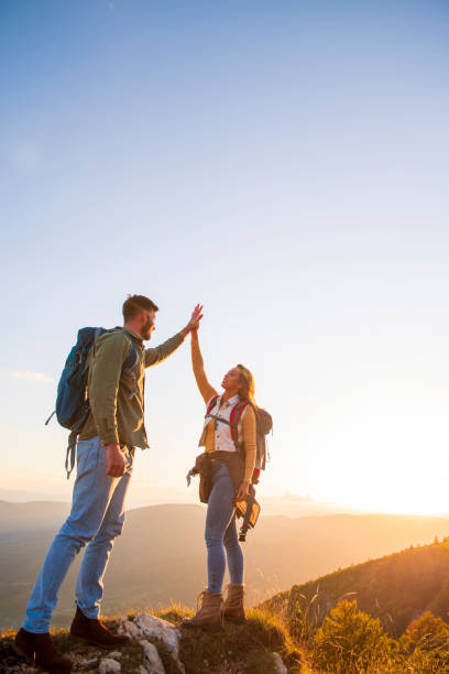istock Couple on Top of a Mountain Shaking Raised Hands 1220884719