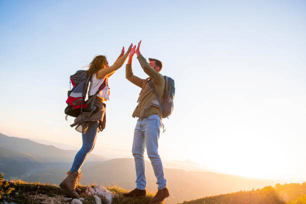 istock Couple on Top of a Mountain Shaking Raised Hands 1220884900