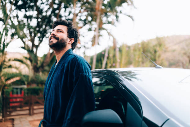 istock Young man wearing a bathrobe leaning on his car 1220884970