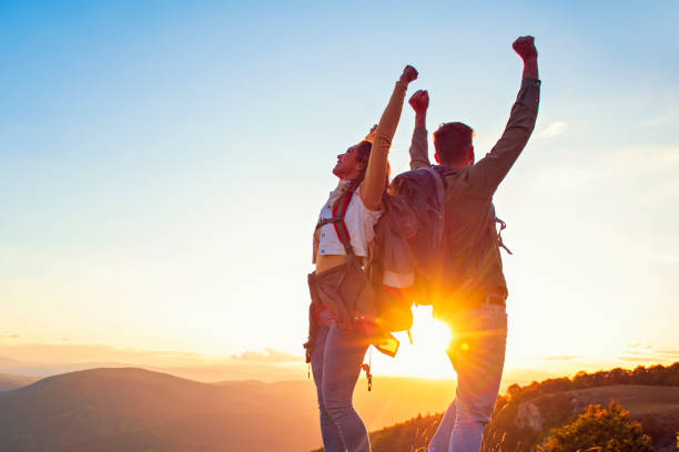 istock Couple on Top of a Mountain Shaking Raised Hands 1220885009