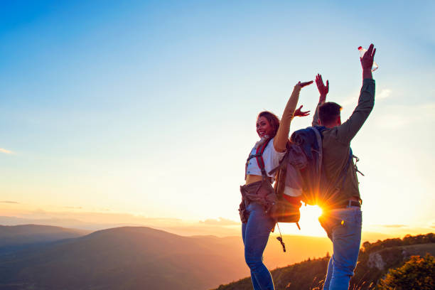 istock Couple on Top of a Mountain Shaking Raised Hands 1220885163