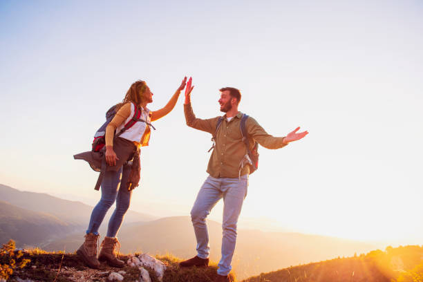 istock Couple on Top of a Mountain Shaking Raised Hands 1220885702