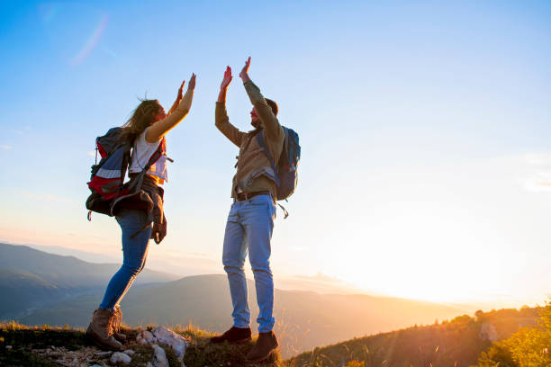 istock Couple on Top of a Mountain Shaking Raised Hands 1220885720