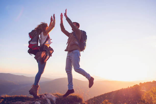 istock Couple on Top of a Mountain Shaking Raised Hands 1220885929