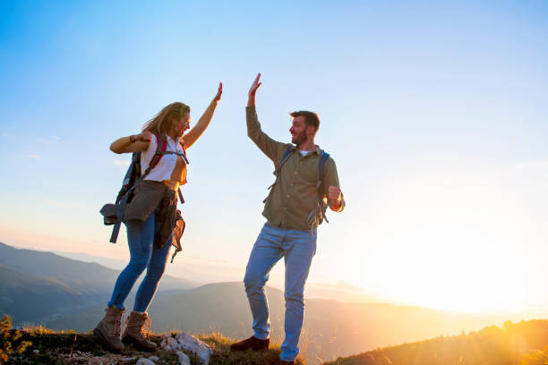 istock Couple on Top of a Mountain Shaking Raised Hands 1220885963
