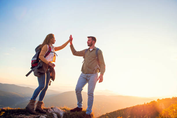 istock Couple on Top of a Mountain Shaking Raised Hands 1220886073