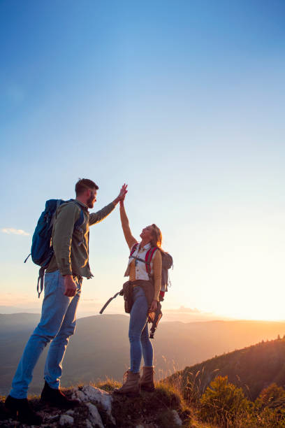 istock Couple on Top of a Mountain Shaking Raised Hands 1220886087