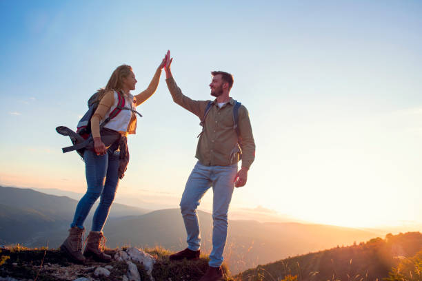 istock Couple on Top of a Mountain Shaking Raised Hands 1220886114