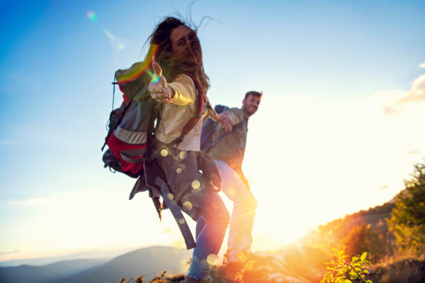 istock People helping each other hike up a mountain at sunrise. 1220886651