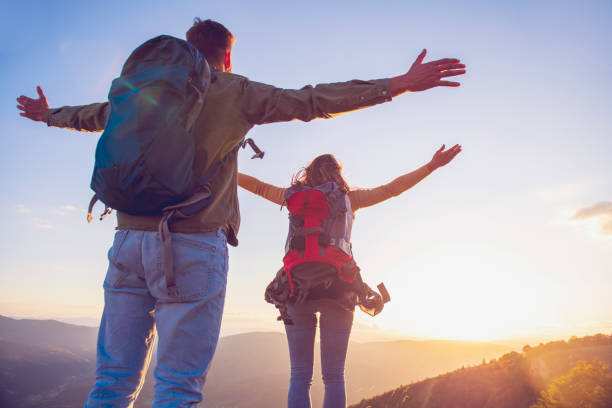 istock Couple with raised arms holding hands and looking at sunset 1220886803