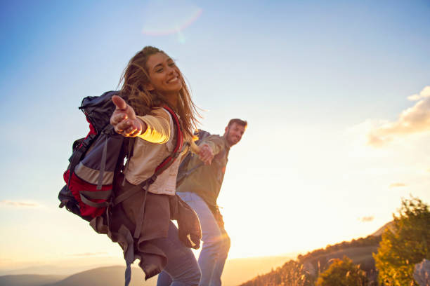 istock People helping each other hike up a mountain at sunrise. 1220886812
