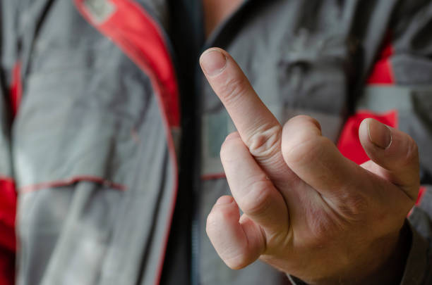 Young man with a vindictive vengeful expression gesturing with his hand towards the camera with focus to his face