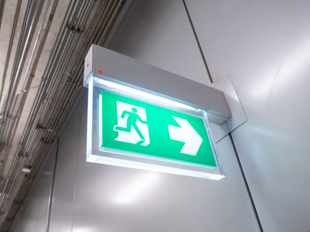 istock led sign in corridor point way out of resident apartment building, Fire warning exit with arrow symbol sign box light Emergency Exit 1220903227