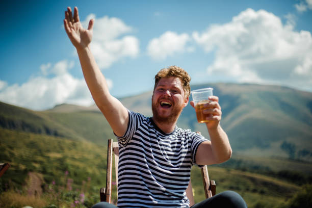 He hiker is resting on top of the mountain with a beer
