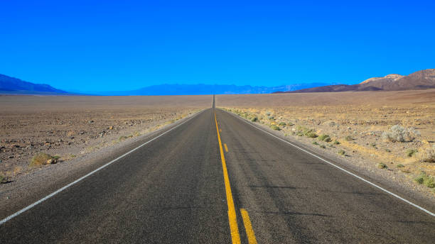estrada sem fim para o parque nacional do vale da morte, califórnia-eua - arid climate asphalt barren blue - fotografias e filmes do acervo
