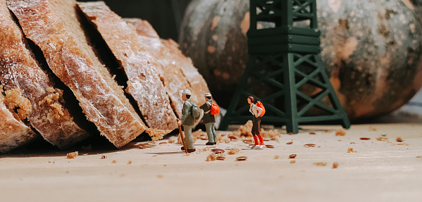 a group of figurine hikers at the loaf of bread , dough with tower