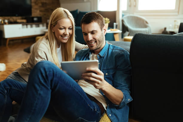 istock Happy couple using digital tablet while relaxing in the living room. 1220908245