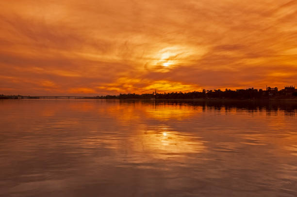 View across large wide river Nile in Egypt through rural countryside landscape with beautiful orange sunset
