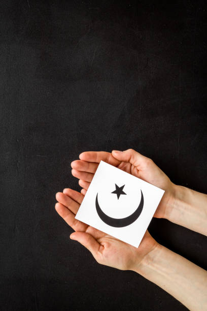 istock Islam sybmbol crescent and star in hands on black table top view copy space 1220912959