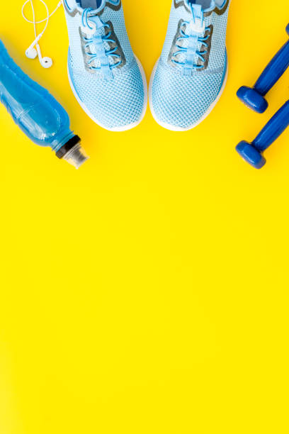 istock Sport set with dumbbells and sneakers on yellow background top-down copy space 1220913289