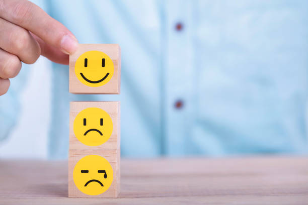 Businessman chooses a smile emoticon icons face happy symbol on wooden block , Services and Customer satisfaction survey concept stock photo