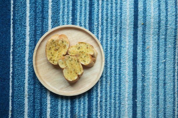 Tasty bread with garlic served on wood dish. Top view