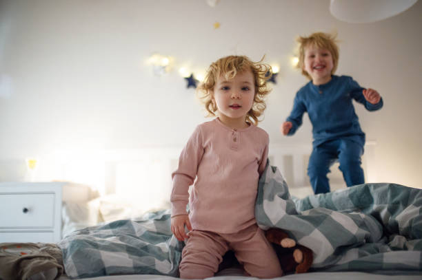istock Two small children jumping on bed indoors at home, having fun. 1220925216