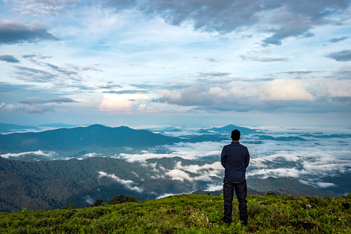 man isolated feeling the serene nature at hill top with amazing cloud layers in foreground image is showing the breathtaking beauty of nature at south india.