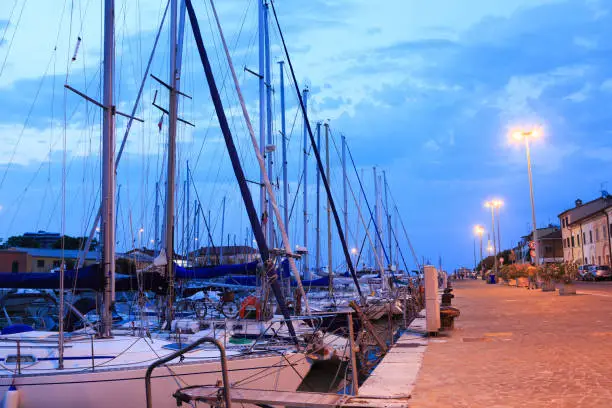 Photo of Pesaro harbour in the night with ancient buildings, ships, yachts. Marche, Italy