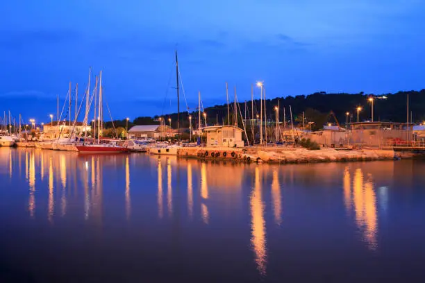 Photo of Yachts moored in the harbor channel in Pesaro, Marche, Italy. Night view.