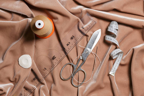 istock Scissors and sewing accessories on a beige fabric background. Top view. 1220933566