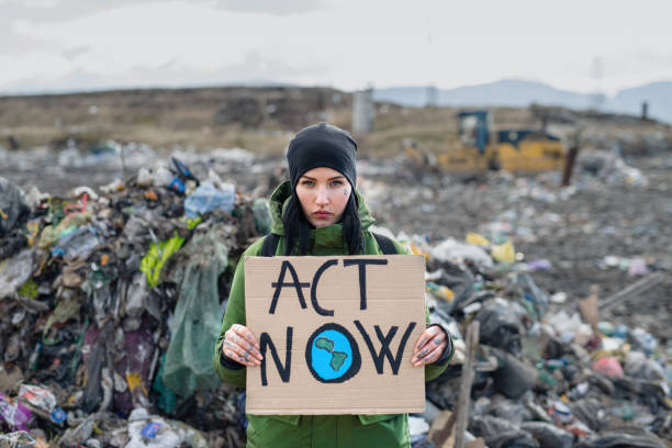 Woman activist with placard poster on landfill, environmental pollution concept. Woman activist holding placard poster on landfill, environmental pollution concept. environmentalist stock pictures, royalty-free photos & images